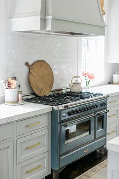 a stove top oven sitting inside of a kitchen next to white cabinets and counter tops