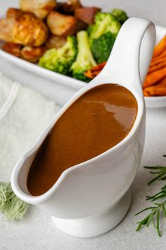 a white gravy dish with carrots and broccoli in the background