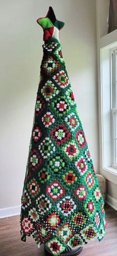 a crocheted christmas tree sitting on top of a wooden floor next to a window