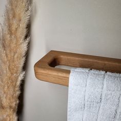 a wooden towel rack next to a toilet paper roll on a wall with a feather hanging from it