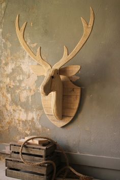 a wooden deer head mounted to the side of a wall next to stacks of wood crates