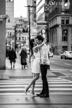 a man and woman kissing in the middle of a crosswalk on a city street