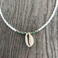 Collier boho coquillage blanc cauri et perles blanches Découvrez la mode bohème chic avec ce superbe collier coquillage boho blanc ! Cette parure est un véritable symbole de liberté, qui vous fera vivre au jour le jour comme une vraie femme boho. Cette chaine est sertie de petites perles blanches, vertes et dorées, pour un style sobre mais élégant. En guise de pendentif, et pour être encore plus dans la tendance des accessoires fantaisies marins, un cauri. Cette délicate coquille est d'un blanc Leaf Earrings Silver, Organic Earrings, Jewelry Friendship, Cowrie Shell Necklace, Necklace Shell, Shell Choker, Dainty Choker, Celtic Knots