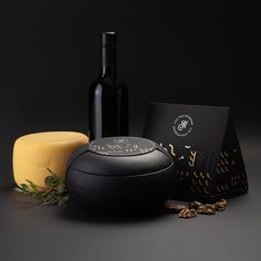 an assortment of wine and cheeses on a black surface with a bottle in the background