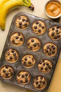 a muffin tin filled with chocolate chip cookies next to a banana and peanut butter