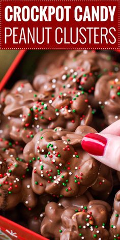 a close up of a person picking up some candy from a red box with white and green sprinkles