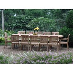 an outdoor table and chairs set up in the middle of a garden with purple flowers