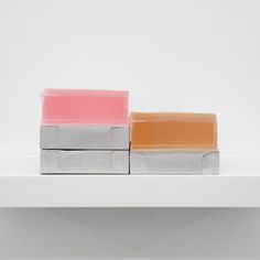 three soap bars sitting on top of a white shelf