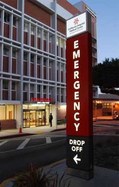 an emergency sign in front of a large building at night with the word drop off on it