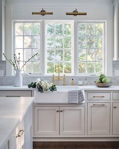 a kitchen with white cabinets and gold faucet handles on the windowsills