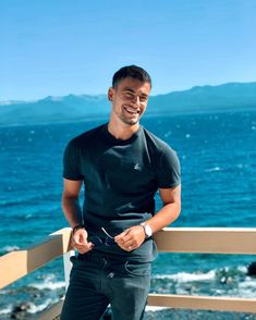 a man standing on a balcony next to the ocean