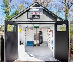 a basketball hoop in the back of a small white building with black doors and windows