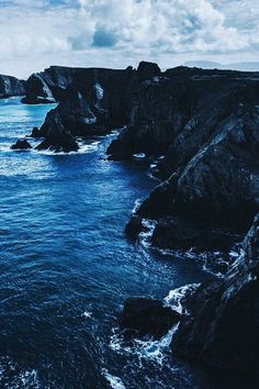 an ocean view with rocks in the foreground and blue water on the far side