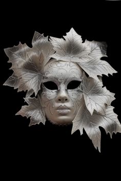 a white mask with leaves on it's head and the face of a woman