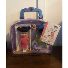 an action figure in a plastic case with a doll and toy animal on the table