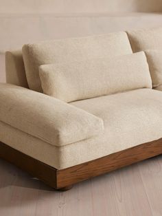 a beige couch sitting on top of a hard wood floor next to a white wall