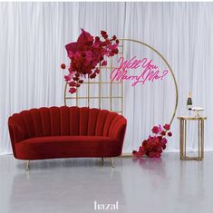 a red couch sitting in front of a white backdrop with pink flowers on the back