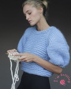 a woman in a blue sweater is knitting