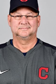 a man in a baseball uniform with a hat on his head and glasses over his eyes