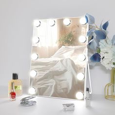 a vanity mirror with lights on it next to flowers