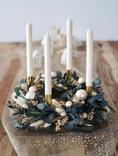 a table topped with candles and greenery on top of a wooden table covered in gold dots