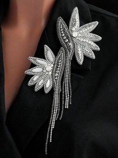 the back of a woman's black jacket with white flowers and pearls on it