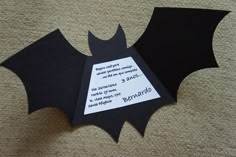 an origami bat cut out from black paper on a brown carpet with white lettering