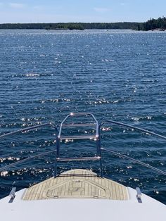 the back end of a boat traveling across a body of water with trees in the background