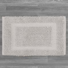 a white rug on top of a wooden floor next to a gray wall and wood floors