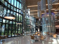 the inside of a large building with many tables and chairs in front of huge windows