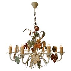 a chandelier with many candles and flowers on the bottom one light is hanging down