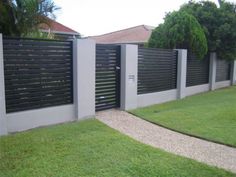 a fenced in area with grass and bushes next to the house that is built into it