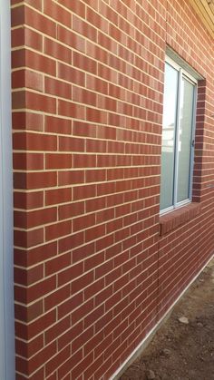 a red brick building with a white door and window on the side of the building