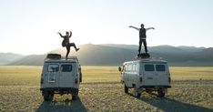 two people standing on top of an off - road vehicle in the middle of nowhere