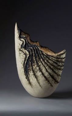 a black and white vase with wavy lines on it's side, against a gray background