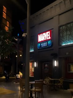 the outside of a restaurant with tables and chairs in front of it at night time