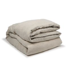 two linen blankets folded on top of each other, one is white and the other is beige