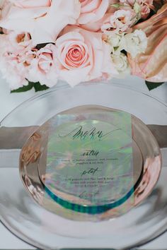 a plate with a wedding program on it next to some pink roses and other flowers