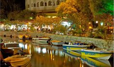 several boats are docked in the water near a building and trees at night with lights on