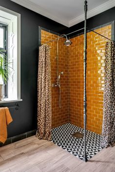 a bathroom with black and white tile, orange shower curtain, and cheetah patterned floor tiles