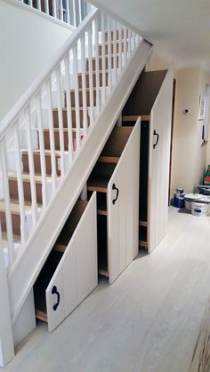 an under the stairs storage unit in a house with white walls and wood flooring