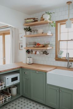 the kitchen is clean and ready to be used for cooking or baking, with green cabinets and white subway walls