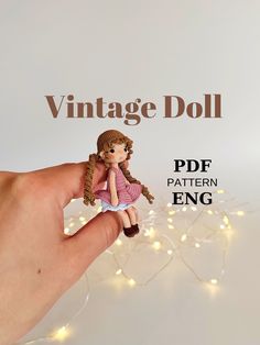 a small doll sitting on top of a hand next to a string of fairy lights