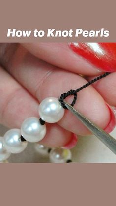 a person holding a pair of scissors and some pearls on the end of a string