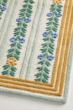 a close up of a rug on the floor with blue and yellow flowers in it