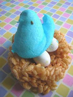 a blue bird sitting on top of a nest filled with rice krispy kreme