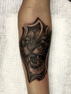 a black and grey tattoo on the leg of a man with a lion head in it