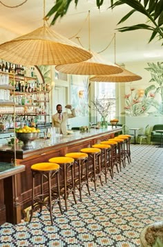 a bar with yellow stools and umbrellas hanging from the ceiling