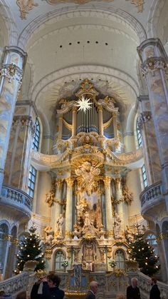 the inside of a church with people standing in front of it and an organ hanging from the ceiling