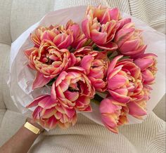 a bouquet of pink flowers sitting on top of a white couch next to a person's arm